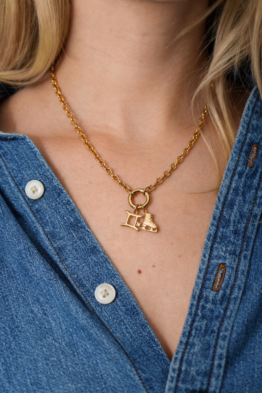 Gold Gemini and ice skate charms on a necklace worn with denim
