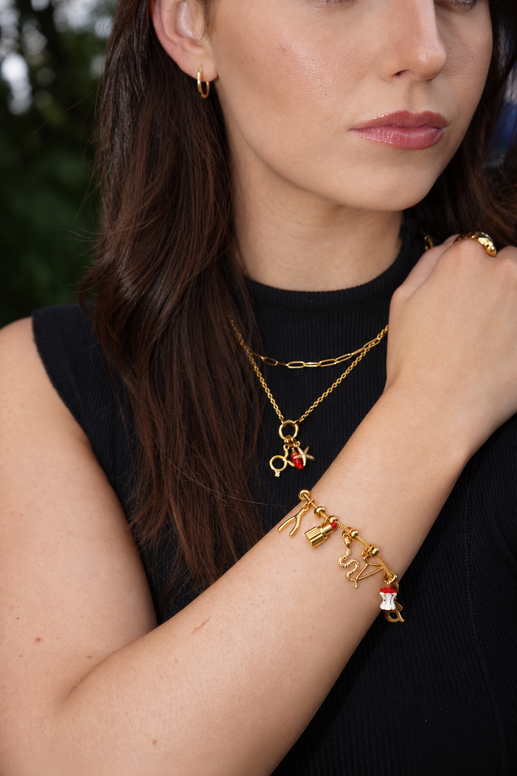 Gold charm jewelry necklace and bracelet worn with black clothing